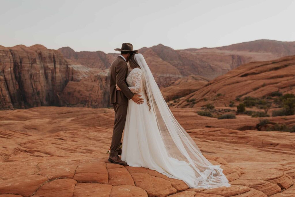 A bride and groom holding each other next to Snow Canyon State park.