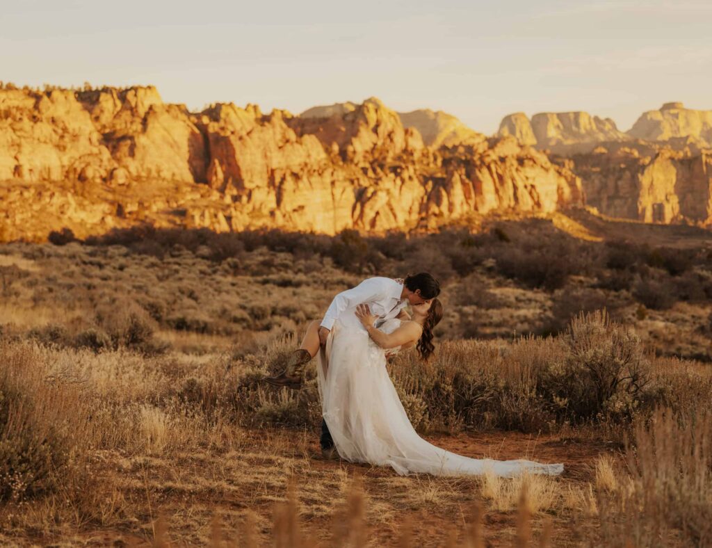 A bride and groom sharing a dip kiss on the outskirts of Zion National Park