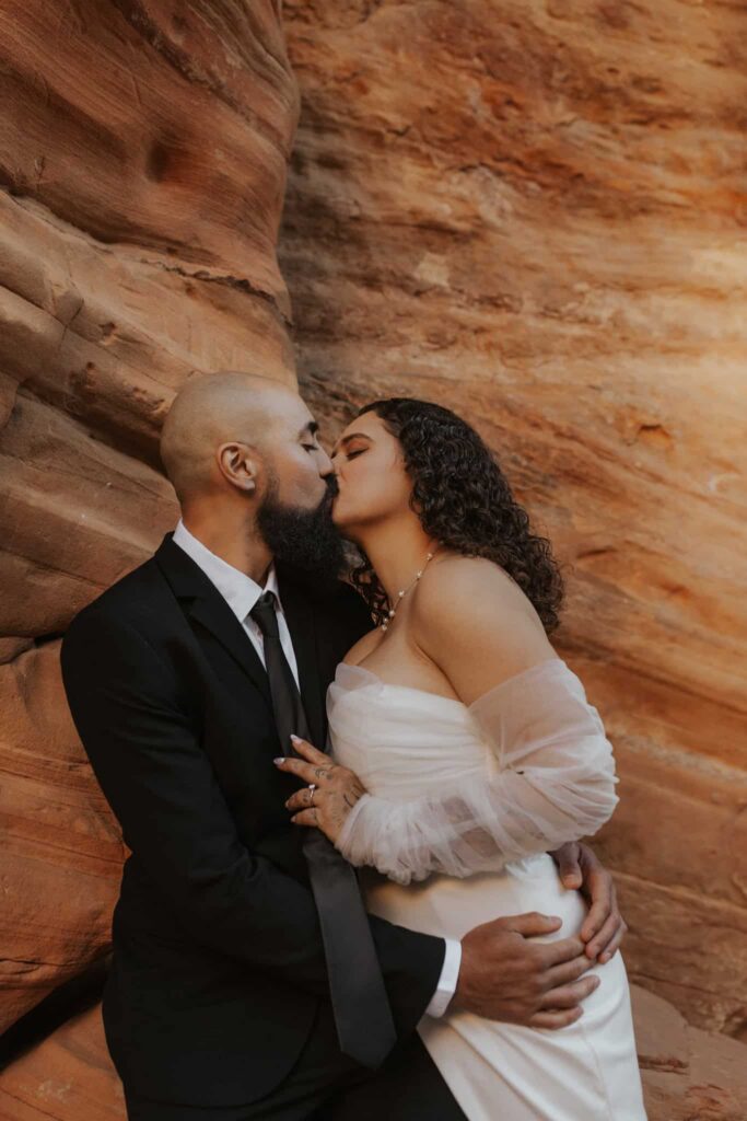 A bride and groom kissing inside a slot canyon in Zion