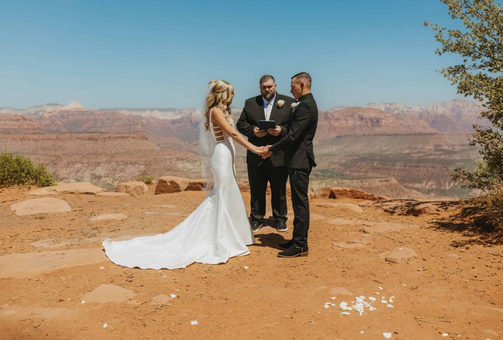 A bride and groom and their officiant at their ceremony in Zion National Park during the summer