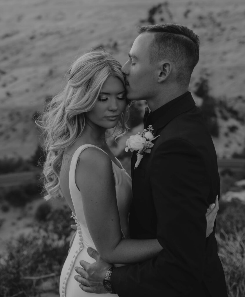 A groom kisses his brides head as they hold each other in Zion.