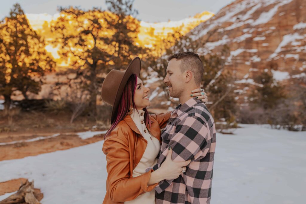 A couple smiling with a beautiful snowy backdrop in Zion National Park.