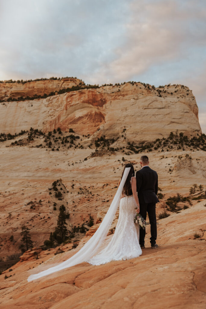 An elopement couple holding each other starting at a beautiful sunset on a ledge in Zion National Park.