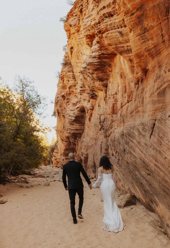 Bride and Groom walking next to a slot canyon with fall colors. 