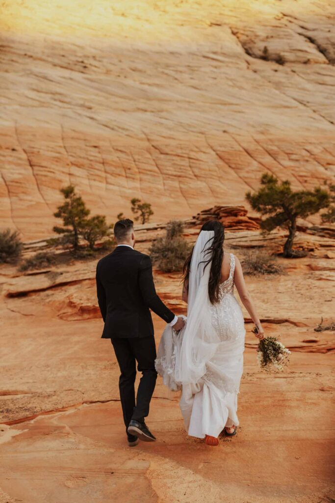 A Bride and groom hiking their wedding attire. 