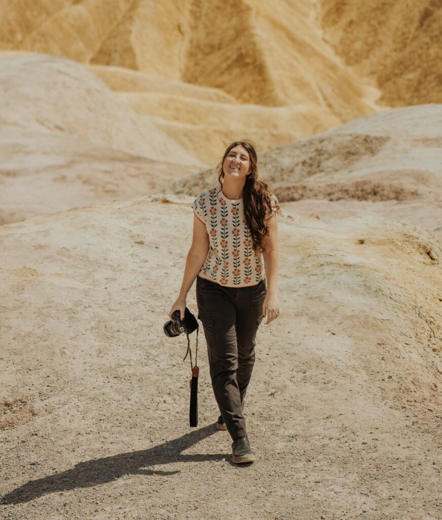 A Bryce canyon elopement photographer smiling while holding her camera and walking.