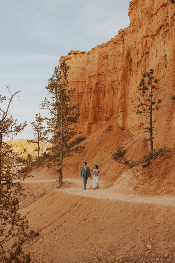 A bride and groom walking on a trail in Bryce Canyon National Park
