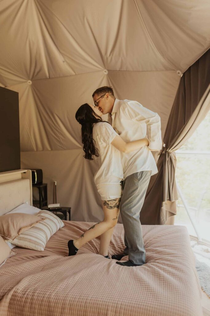 A couple kissing while jumping on their bed.