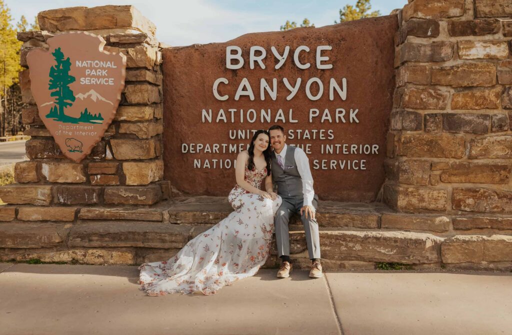 A newly married couple poses in font of the National Park Sign at Bryce Canyon